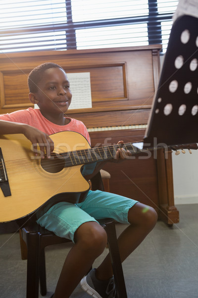 Happy boy playing guitar while sitting in classroom Stock photo © wavebreak_media