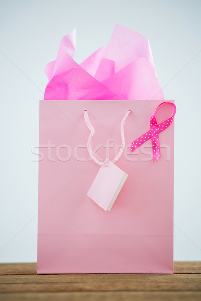 Stock photo: Close-up of pink Breast Cancer Awareness ribbon on shopping bag over wooden table