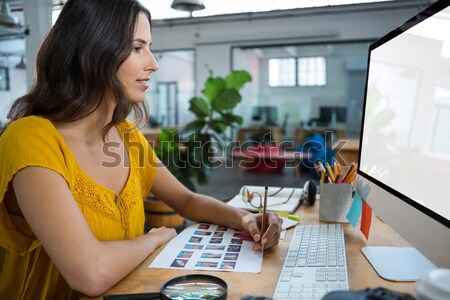 Stock photo: Female executive working over graphic tablet at her desk in office