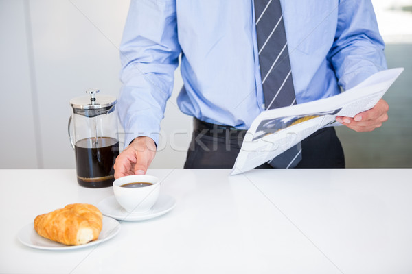 Businessman holding coffee cup and newspaper by table Stock photo © wavebreak_media