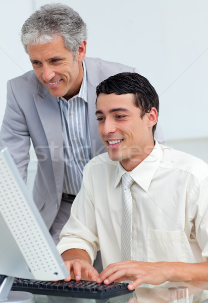 Stock photo: Mature businessman helping his colleague at a computer