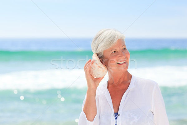 Mujer madura escuchar Shell mujer playa nina Foto stock © wavebreak_media