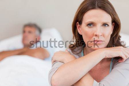 Stock photo: Sad woman on the bed with her husband in the background