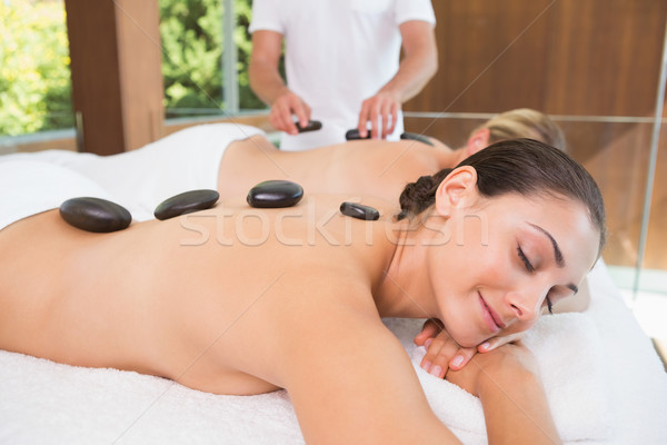 Happy friends lying on massage tables with hot stones on their b Stock photo © wavebreak_media