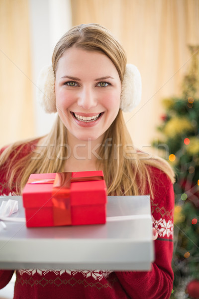 Smiling blonde wearing earmuffs while holding gifts Stock photo © wavebreak_media