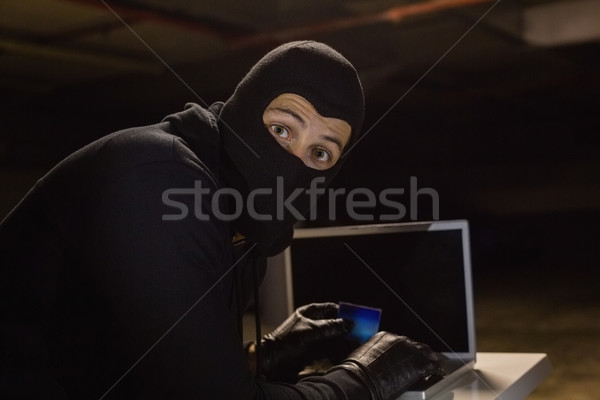Burglar shopping online with laptop while looking at camera Stock photo © wavebreak_media