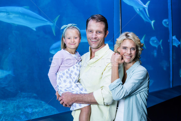 Happy family looking at camera beside the fish tank Stock photo © wavebreak_media