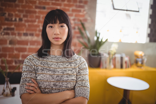 Stock photo: Portrait of confident beautiful young woman standing with arms crossed