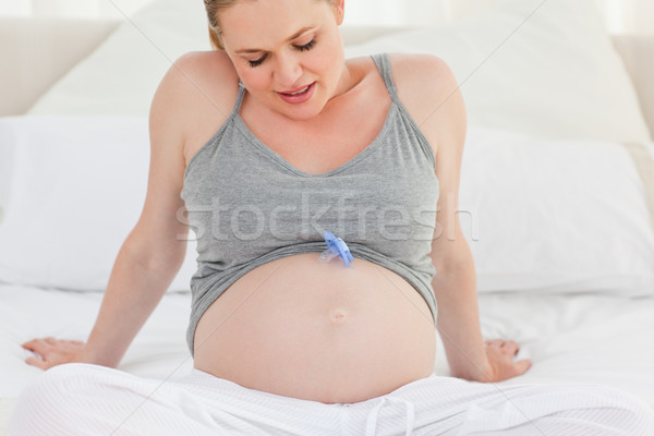 Pregnant woman with a baby dummy on her belly at home Stock photo © wavebreak_media