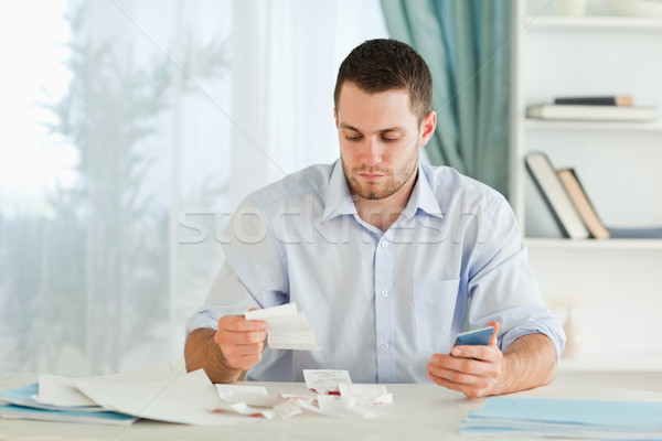 Stock photo: Young businessman with pocket calculator checking invoices