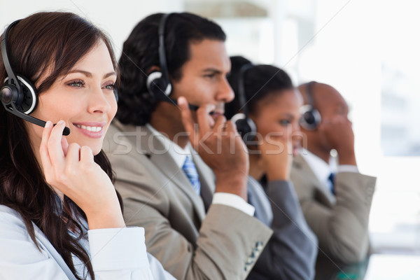 Young smiling call centre employee working hard and accompanied by her team Stock photo © wavebreak_media