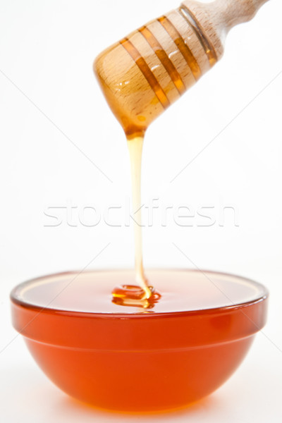 Stock photo: Honey trickle dropping in bowl against a white background