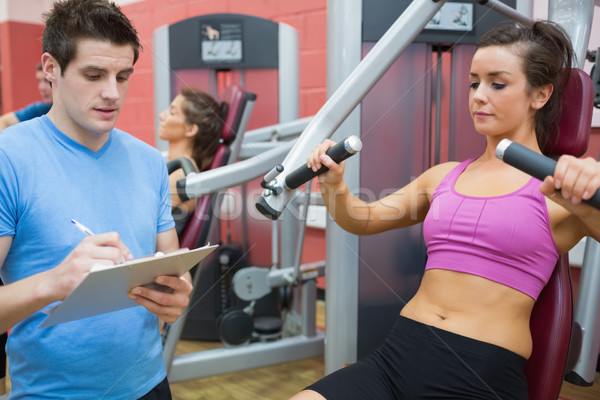 Trainer taking notes on client on weights machine Stock photo © wavebreak_media