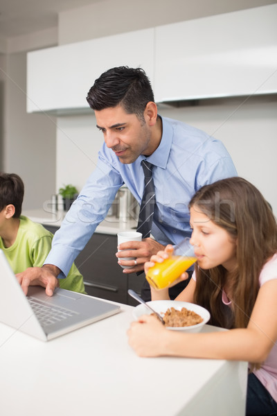 Father using laptop and kids having breakfast in kitchen Stock photo © wavebreak_media