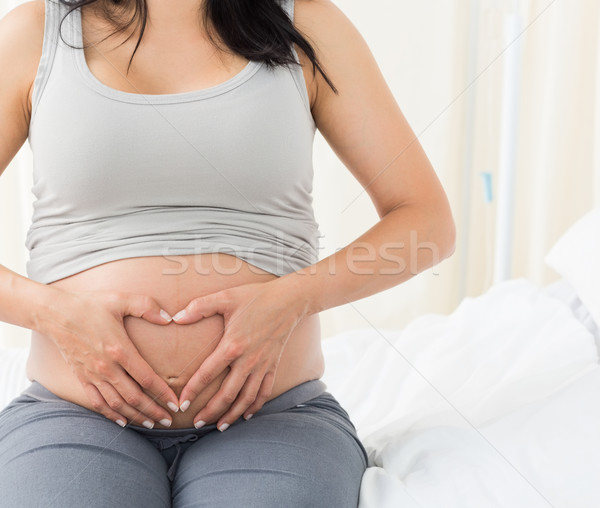 Femeie gravida forma de inima burtă şedinţei pat de spital Imagine de stoc © wavebreak_media