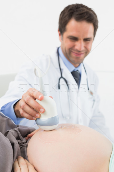 Happy doctor doing a sonogram scan on pregnant woman Stock photo © wavebreak_media