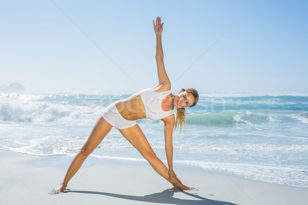 Gorgeous blonde standing in extended triangle pose by the sea Stock photo © wavebreak_media