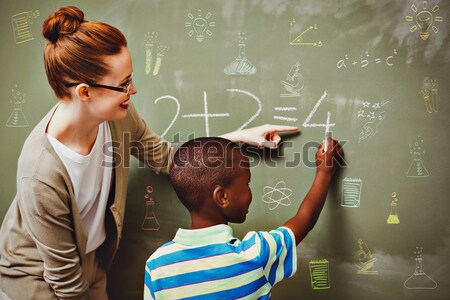 Teacher assisting boy to write on blackboard in classroom Stock photo © wavebreak_media