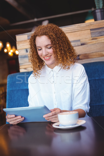 Stock photo: Pretty girl using a small tablet at table