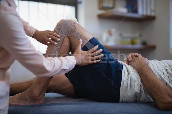 Midsection of female therapist measuring knee while senior male patient lying on bed Stock photo © wavebreak_media