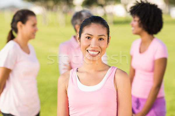 Smiling woman wearing pink for breast cancer in front of friends Stock photo © wavebreak_media