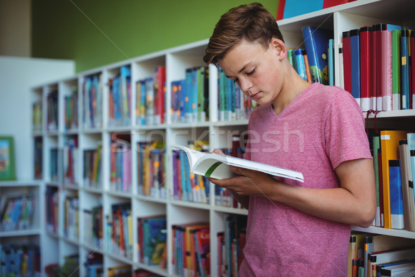Attentive schoolboy reading book in library Stock photo © wavebreak_media