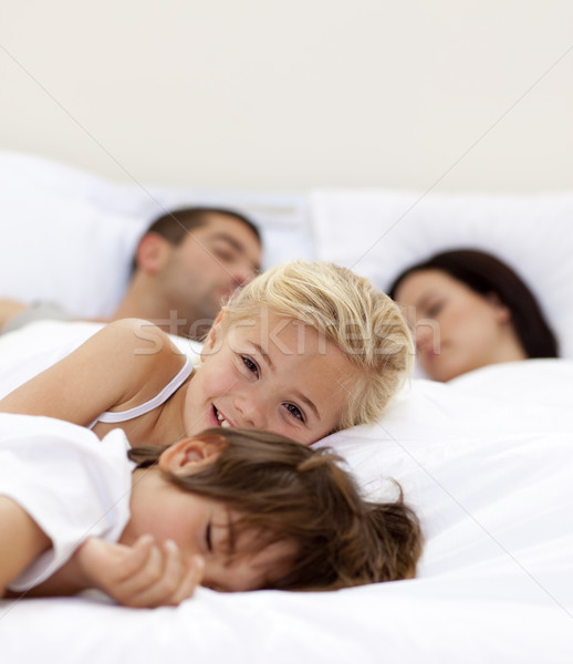 Little girl smiling wile her parents and brother sleep Stock photo © wavebreak_media