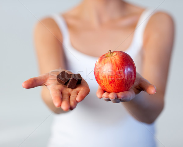 Stock photo: Beautiful woman showing chocolate and apple focus on chocolate 
