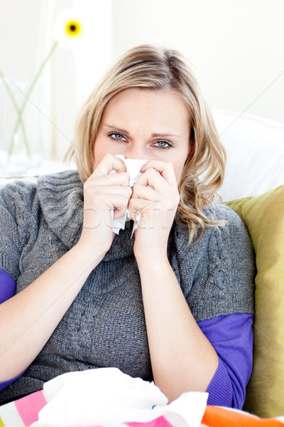 Sick woman using a tissue sitting on a sofa at home Stock photo © wavebreak_media