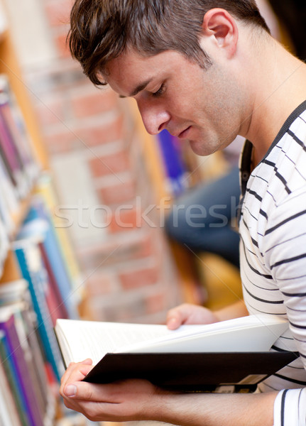 Stock photo: Serious young man reading a book in a bookstore