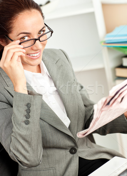 Smiling businesswoman with glasses and a newspaper sitting at her desk Stock photo © wavebreak_media