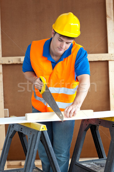 Handsome male worker wearing a yellow hardhat sawing a wooden board Stock photo © wavebreak_media