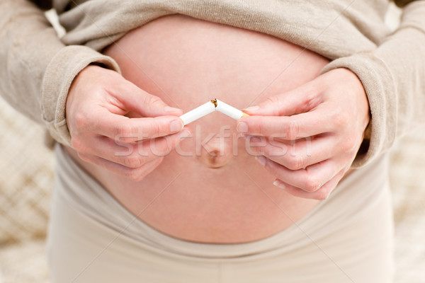 Close up of an attentive pregnant woman breaking a cigarette standing in the living room Stock photo © wavebreak_media