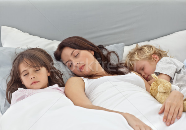 Adorable children sleeping with their mother on her bed at home Stock photo © wavebreak_media