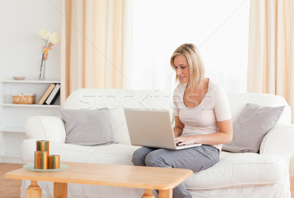 Blonde woman using a laptop while sitting on her sofa Stock photo © wavebreak_media