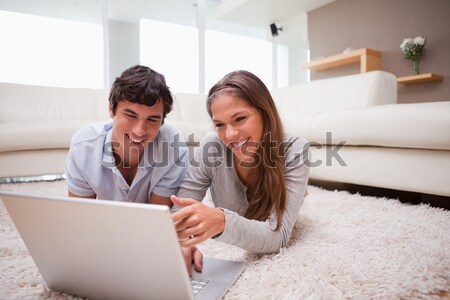 Stock photo: Young couple lying on the floor booking holidays online