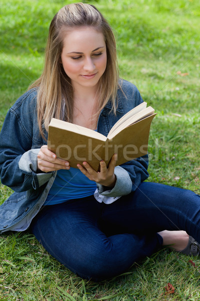 Young peaceful girl reading a book while sitting on the grass in a public garden Stock photo © wavebreak_media