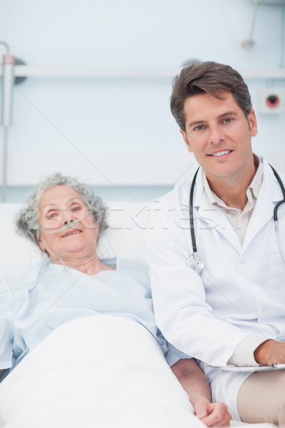 Doctor and patient on the bed looking at camera in hospital ward Stock photo © wavebreak_media