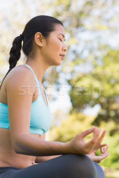 Stock photo: Sporty woman in lotus pose with eyes closed at park