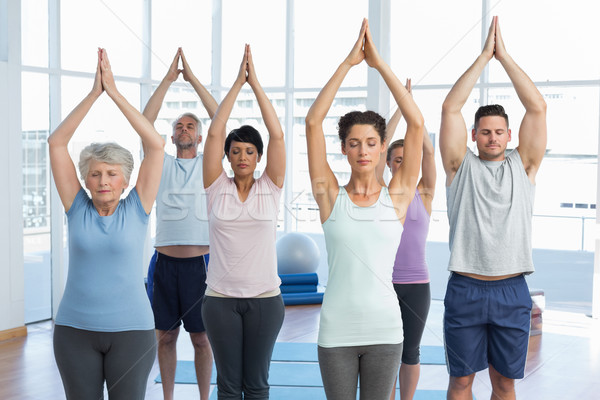 People with eyes closed and joined hands at fitness studio Stock photo © wavebreak_media