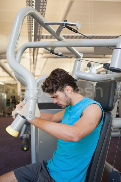 Stock photo: Focused man using weights machine for arms