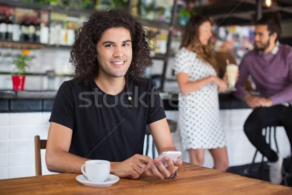 Portré fiatalember tart mobiltelefon ül étterem Stock fotó © wavebreak_media