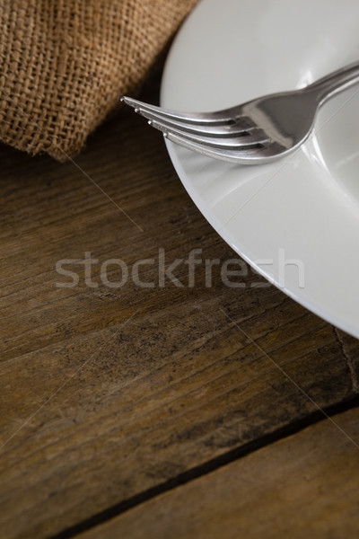 Stock photo: White plate and fork on wooden table