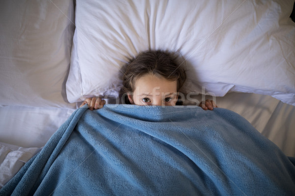 Girl covering her face under the blanket while lying on bed Stock photo © wavebreak_media