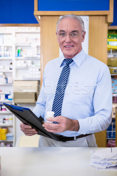 Pharmacist holding a medicine container and clipboard Stock photo © wavebreak_media