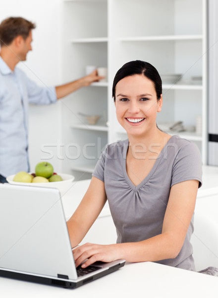 Happy woman working on the laptop in the kitchen with her boyfriend in the background Stock photo © wavebreak_media