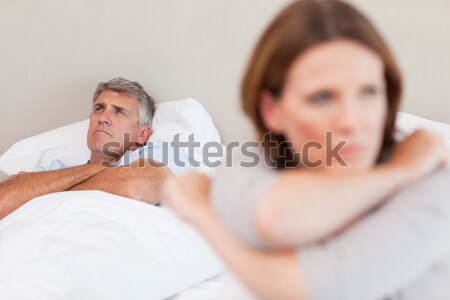 Stock photo: Tired man having a headache sitting on the bed with his girlfriend