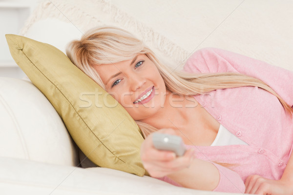 Gorgeous blonde woman posing while lying on a sofa in the living room Stock photo © wavebreak_media