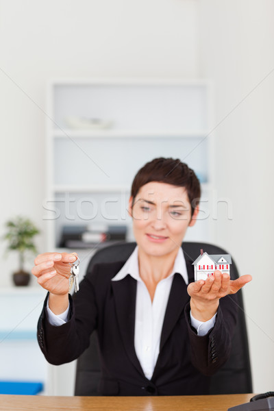 Portrait of a woman showing a miniature house and a key in her office Stock photo © wavebreak_media