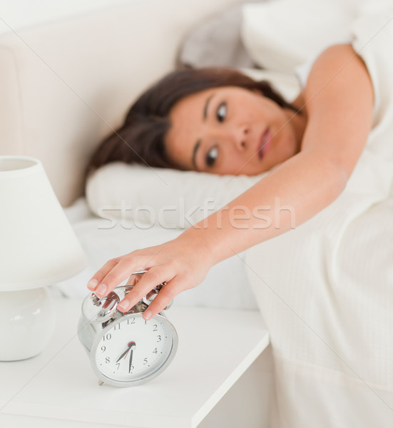 charming woman waking under sheet turning off alarm clock in bedroom Stock photo © wavebreak_media